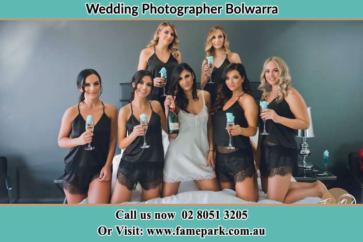 The bride holding a bottle of wine poses with the girls in front of camera Bolwarra