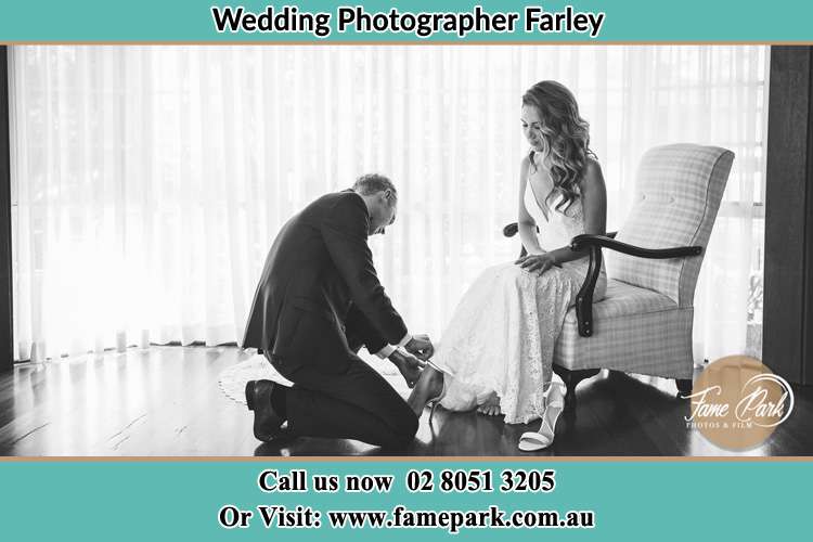 The Bride is being helped by the Groom trying to put on her shoes Farley