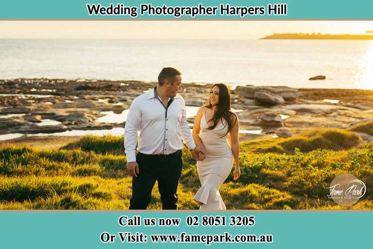 Photo of the Groom and the Bride walking near the shore as they look at each other Harpers Hill