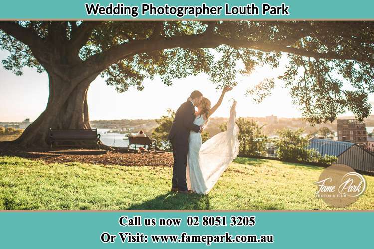 Photo of the new couple kissing under a big tree Louth Park