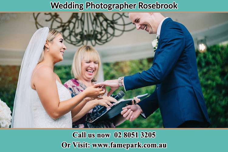 The Groom and the Bride holding their hands while the pastoress is watching Rosebrook